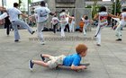 A young skateboarder passes by as Grupo Candeias perform their acrobatics and energetic music at Eyre Square as part of the Capoeira Festival at the weekend. Capoeira is a blend of martial art, acrobatics, music, and dance that originated in Brazil. The event was hosted by the local Grupo Candeias who train twice a week with Contra Mestre Mola at Creaven House in the Claddagh.
