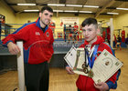 Olympic Boxing Club had 6 members competing last week to get through to the National Schoolboy Championships. They were successful with 3 of the boxers getting through to the Final with one Champion.<br />
Brandon Mongan won the Boy 3 48kg National Title beating Sean McGenity, Silverbridge Boxing Club, Armagh, on a 2-1 Split decision in Saturday's final. It was Brandon's 3rd win that week after beating David Nevin, Holy Family Boxing Club, Drogheda 3-0 unanimous in the Quarter final and beating Christopher Fisher, Oliver Plunkett Boxing Club, Belfast 3-0 in the semi final. Brandon is both the Galway County and Connacht Boy 3 48kg Champion.<br />
Eddie ward was narrowly defeated on a 2-1 split decision in the Boy 1 63kg final to Darren Darcy of Mullinahone Boxing Club, Tipperary, and Jamie Delaney just lost out on a 2-1 Split decision to Barry O'Connor, Sliabh Lurcha Boxing Club, Castleisland Kerry, in the Boy 2 39kg final.<br />
This weekend the club have 10 boxers through to the National Boy 4, Youth 1 and Youth 2 Championships.<br />
Boy 3 48kg champion Brandon Mongan is pictured this week, with his medals and certificates, with the Olympic Boxing Club Head Coach, Michael Mongan.